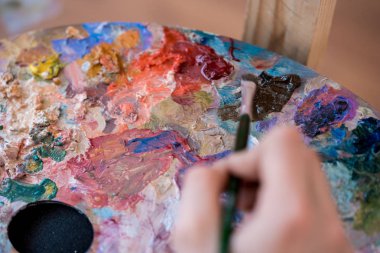 Ressam, boya fırçasının resmini palet kaplamalı olarak çiziyor.