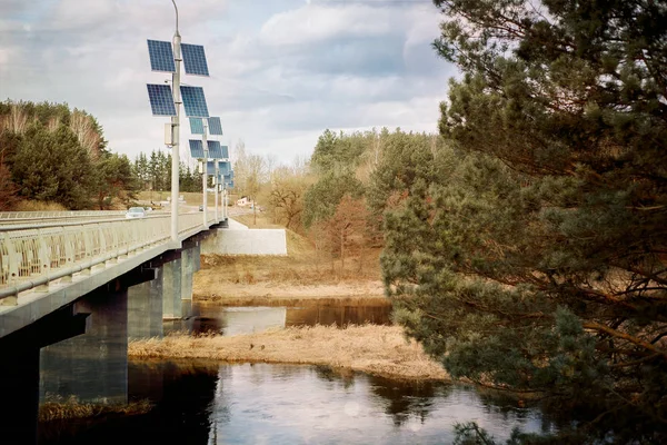 solar panels in the forest. bridge and river in spring. ecology