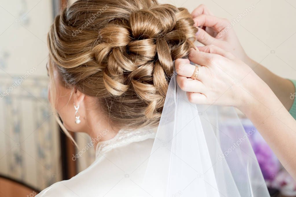 Blonde bride hairstyle. white veil. stylist helps the bride at home