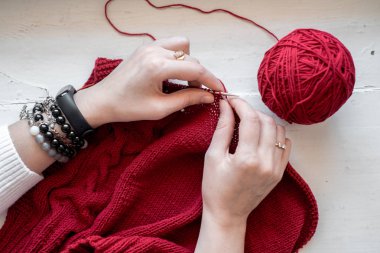 Tüm iğne için: kırmızı iplik, örgü, ahşap gri bir masa üzerinde iğne örgü. Üst te. kaybetmek.. Kopyalama alanı.