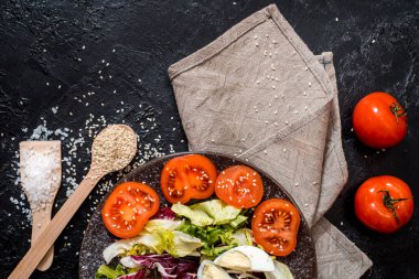 Siyah arka plandaki sebzeler. Organik gıdalar ve taze sebzeler. Salatalık, lahana, biber, salata, havuç, brokoli, marul ve domates masada.