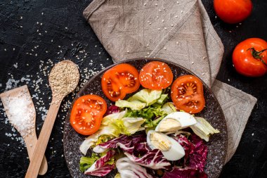 Siyah arka plandaki sebzeler. Organik gıdalar ve taze sebzeler. Salatalık, lahana, biber, salata, havuç, brokoli, marul ve domates masada.