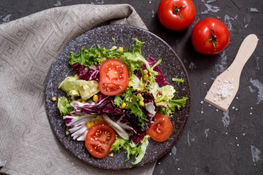 Mor lahanalı taze sebze salatası, beyaz lahana, marul, siyah arka planda koyu kil kasede havuç. Üst görünüm