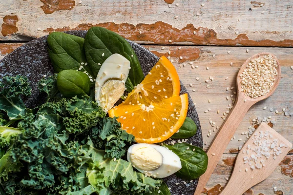 Salad with spinach leaves and eggs in bowl on wooden table