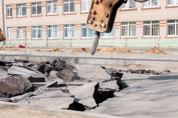 Trapani macchina asfalto. Grandi frammenti di terra e fosse ovunque sulla strada. attrezzature di lavoro con un trapano funziona ad alta voce — Foto Stock