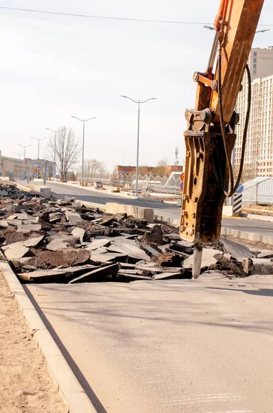 Trapani macchina asfalto. Grandi frammenti di terra e fosse ovunque sulla strada. attrezzature di lavoro con un trapano funziona ad alta voce — Foto Stock