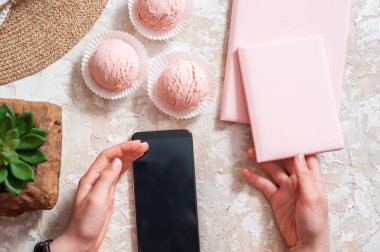 hafif bir arka plan üzerinde çilekli dondurma, yaz kavramı, hasır şapka, pembe defter.