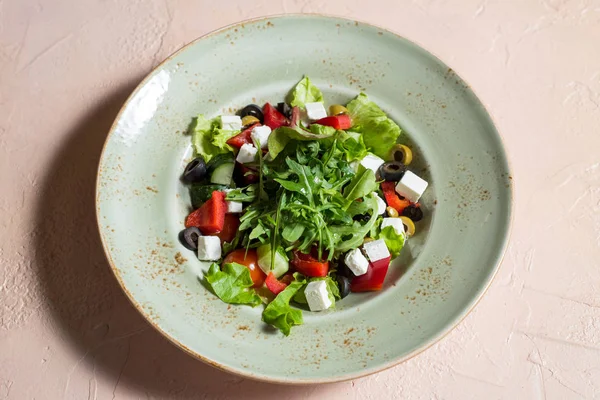 Fresh Greek salad in bowl with black olive,tomato,feta cheese, cucumber and onion on white wooden table. Close up