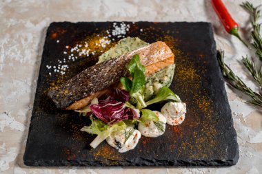 Kavrulmuş somon balık patates, brokoli ve koyu arka plan üzerinde beyaz tabak soslu biftek