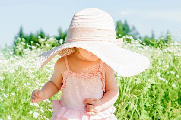 Happy baby boy standing in grass on the fieald with dandelions at sunny summer evening. Smiling child outdoors — Stock Photo, Image