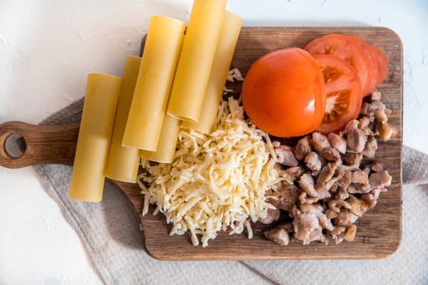 Chef cocinando espaguetis en la cocina. cocinar canelones de pasta. pasta cruda y salsa bechamel sobre un fondo blanco. manos de bebé tomar pasta — Foto de Stock