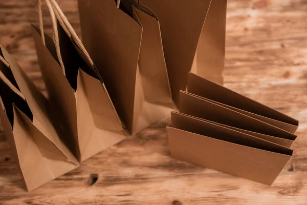 Maqueta de paquete de papel artesanal marrón con asas, bolsa de compras vacía con área para su logotipo o diseño, tablero de madera en el fondo, entrega de alimentos, venta, consumismo y concepto de publicidad . — Foto de Stock