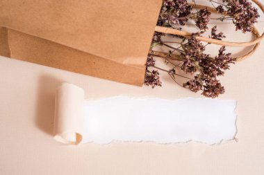 Kraft paketi, çiçeklerle yeniden kullanılabilir ambalaj. Ev yapımı çay, nane, limon merhemi ve çördük çiçekleri. Yırtık kağıt, mocap kartpostal