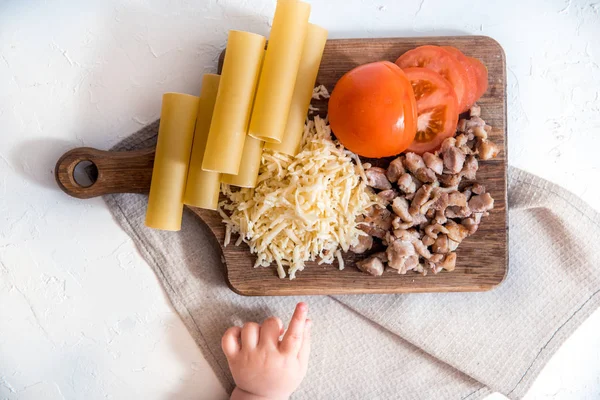 Chef cocinando espaguetis en la cocina. cocinar canelones de pasta. pasta cruda y salsa bechamel sobre un fondo blanco. manos de bebé tomar pasta — Foto de Stock