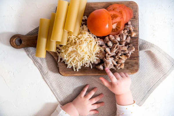 Chef cocinando espaguetis en la cocina. cocinar canelones de pasta. pasta cruda y salsa bechamel sobre un fondo blanco. manos de bebé tomar pasta — Foto de Stock