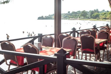 Sahilde deniz restoranı. Kırmızı kadife sandalyeler. Lüks masa ayarı. Pahalı gün batımı yemeği. Kalite gevşeme kavramı