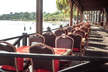 Sahilde deniz restoranı. Kırmızı kadife sandalyeler. Lüks masa ayarı. Pahalı gün batımı yemeği. Kalite gevşeme kavramı