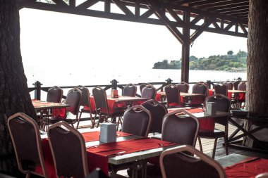 Sahilde deniz restoranı. Kırmızı kadife sandalyeler. Lüks masa ayarı. Pahalı gün batımı yemeği. Kalite gevşeme kavramı