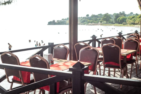 Sahilde deniz restoranı. Kırmızı kadife sandalyeler. Lüks masa ayarı. Pahalı gün batımı yemeği. Kalite gevşeme kavramı