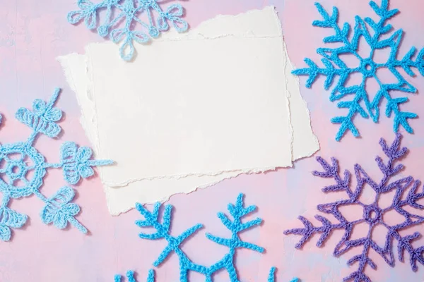 Noel arkaplanı boş defter, mavi örülmüş kar tanesi, mor-pembe arka planda el yapımı. Model yırtık kağıt trendi. Düz yerde, üst tarafta. Boşluğu kopyala.