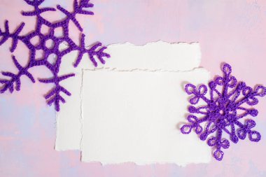 Noel arkaplanı boş defter, mavi örülmüş kar tanesi, mor-pembe arka planda el yapımı. Model yırtık kağıt trendi. Düz yerde, üst tarafta. Boşluğu kopyala.