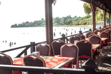 Sahilde deniz restoranı. Kırmızı kadife sandalyeler. Lüks masa ayarı. Pahalı gün batımı yemeği. Kalite gevşeme kavramı