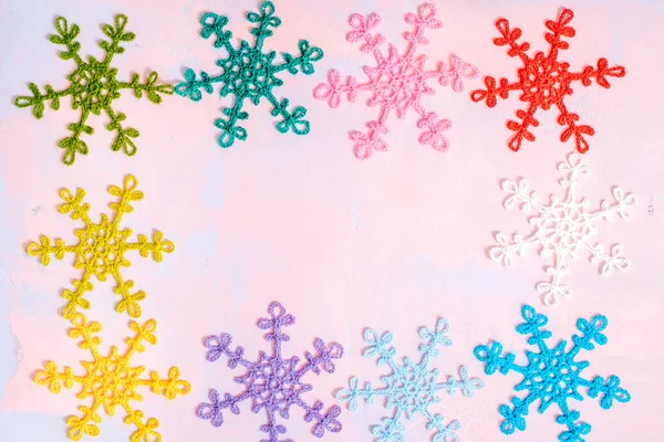 Copos de nieve multicolores de ganchillo. Encaje de ganchillo. Creatividad hecha a mano. Tarjeta de Navidad brillante sobre fondo rosa y púrpura. Plano, vista superior, espacio para copiar . —  Fotos de Stock