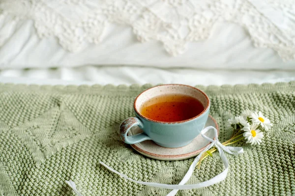 Una tazza di caffè e un libro aperto sul letto bianco aperto. Colazione mattutina. Luminosa giornata accogliente — Foto Stock