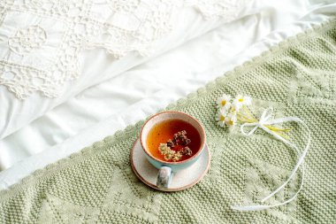 Laptop, bir fincan çay, beyaz yatak ve ekose. Güneşli bir sabah ve kahvaltı. Rahat bir evde internet üzerinden çalışmak. Sıcak, aydınlık oda