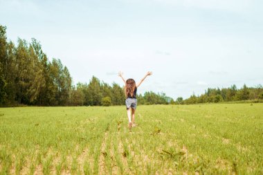 Çiçek tarlasında çayırda koşan küçük bir kız. Yaz günü. Çıplak ayakla çimlerin üzerinde zıplamak, mutlu kahkahalar. Ufuk ve gökyüzü. Tazelik fikri ve özgürlük. Mutlu çocukluk