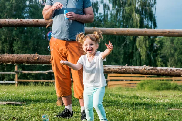 Ojciec Jego Córka Robią Bąbelki Parku Wesoła Piękna Dziewczynka Biegnie — Zdjęcie stockowe