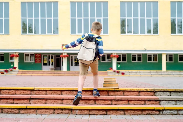 一个背着背包跳起来的小学生的画像 那男孩在学校院子里背着一个背包 幼儿教育 学习概念 — 图库照片