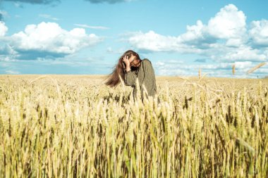 Buğday kulakları. Elbiseli genç kız duygularını gösteriyor. Duygusal olarak atlıyor ve dikenli kazıklarla bir yaz sahasında koşuyor. Kozmetik kavramı, hasat, çiftlik. Rüzgarda uçuşan saçlar, yaşam tarzı.