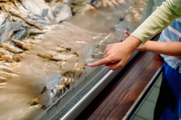 Fresh Frozen Fishes.children draw with their finger on the glass of the freezer