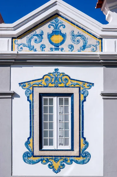 Portekiz 'in Cascais şehrinde geometrik şekilli tipik Portekiz fayansları ve beyaz, mavi ve sarı renklerle dekore edilmiş pencere.