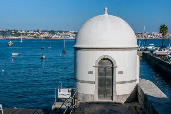 Portekiz 'de, Tagus Nehri' nin önündeki Cascais gelgit ölçer güneşiyle manzarayı seyret.