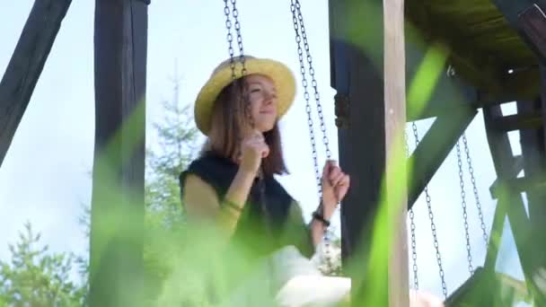 美丽的女孩在草帽摇摆摇摆 木秋千 — 图库视频影像
