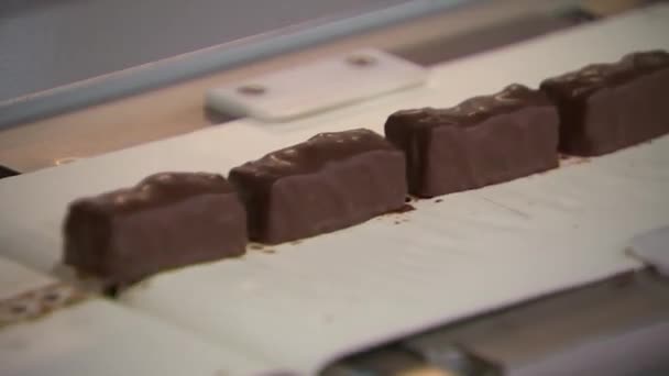 チョコレートのお菓子はコンベアに沿って迅速に移動します — ストック動画