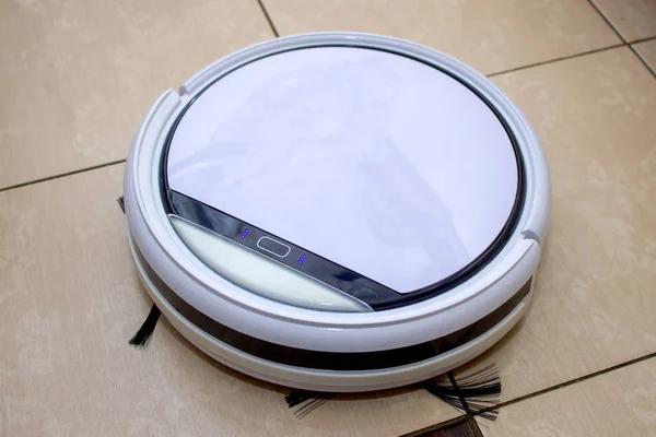 Robot vacuum cleaner working in the kitchen, sweeping debris from the tile floor