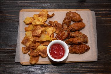 Cips ve kırmızı sos ile tavuk göğsü kızarmış parçalar ahşap bir masa üzerinde