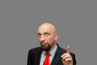 Sakallı kel adam gri arka plana parmak la bakıyor ve işaret