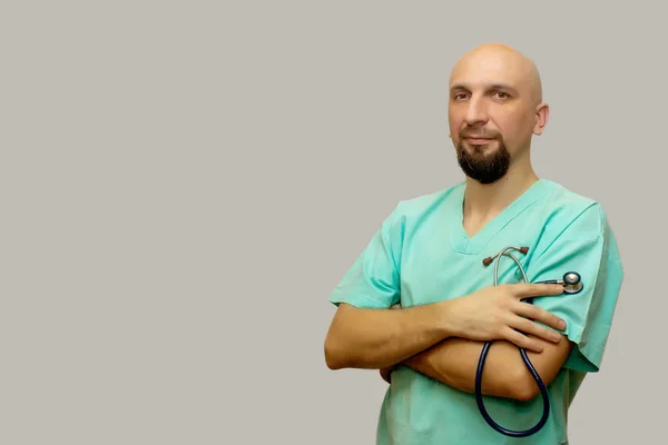 A bald man in the clothes of a doctor holding a stethophonendoscope, a doctor on a gray background