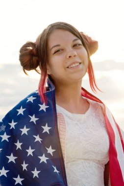 Kız akşam bir Amerikan bayrağı, güneş parlama ve renkli sarılmış oldu