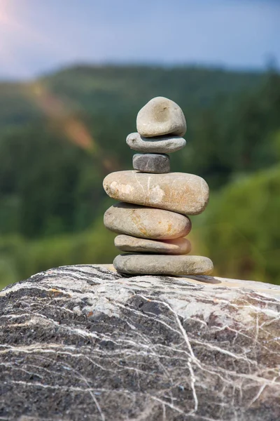 The stones are stacked on top of each other against the background of nature,sun glare and toning