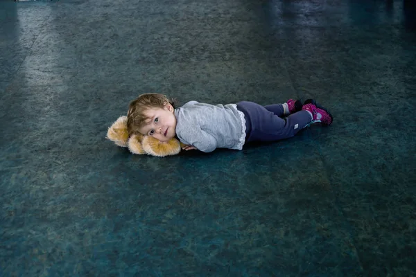 一个小孩躺在冰冷的地板上 他的玩具在他的头下 失去了孩子 — 图库照片