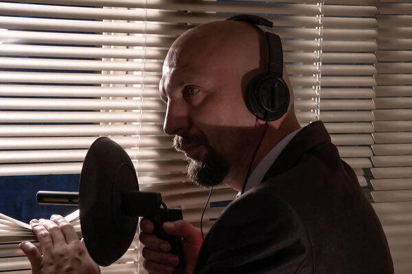 Секретный агент тайно подслушивает направленный микрофон толкая жалюзи, наблюдение и контроль людей, средний план
