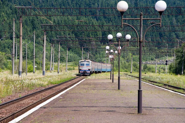 乗用車を搭載した電車が山の駅に到着 — ストック写真