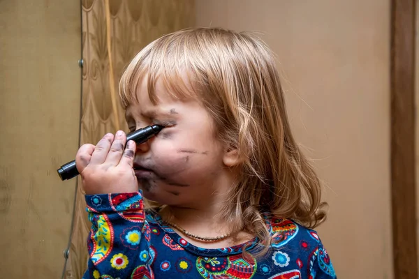 一个小女孩在镜子前用毛笔画她的脸 她是一位年轻的化妆师 孩子气的自发性 渴望成为一个成年人和美丽的人 用自己的双手化妆 — 图库照片