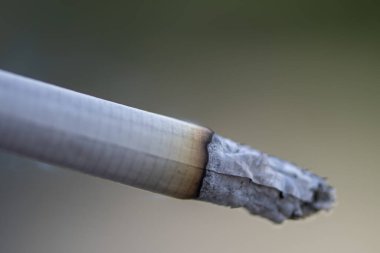 Rüzgarda yanan bir sigara, tütün külleri sarkıyor, yakın plan, seçici odaklanma..