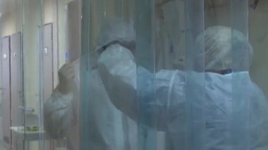 Sağlık personeli, ultraviyole ışık altında, tek kullanımlık antiviral giysiler altında 